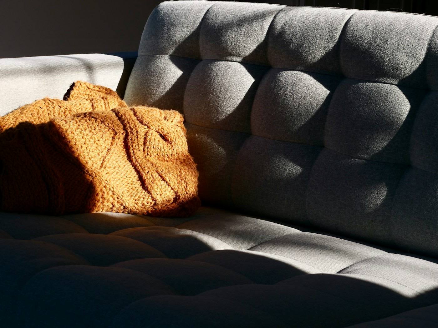 A knitted blanket on a sofa in sunlight