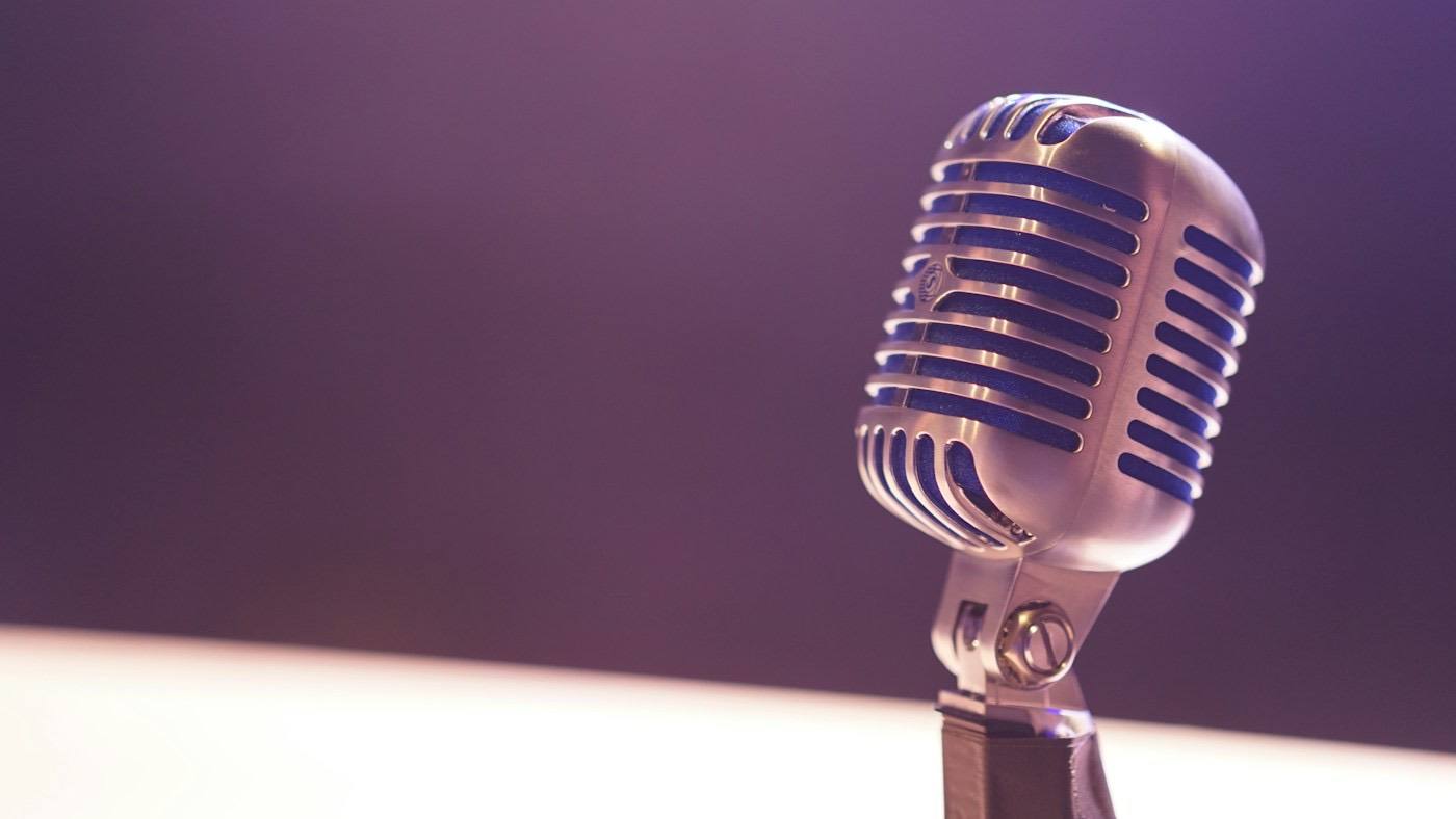 A vintage microphone against a purple background